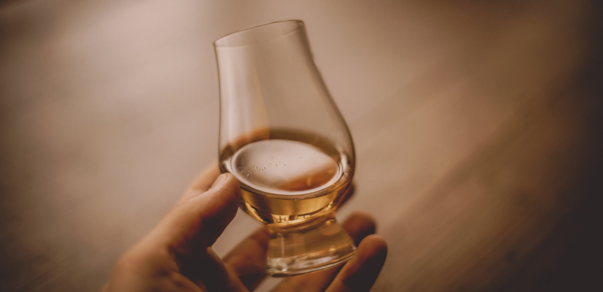 Glass of whisky being held in an open palm with