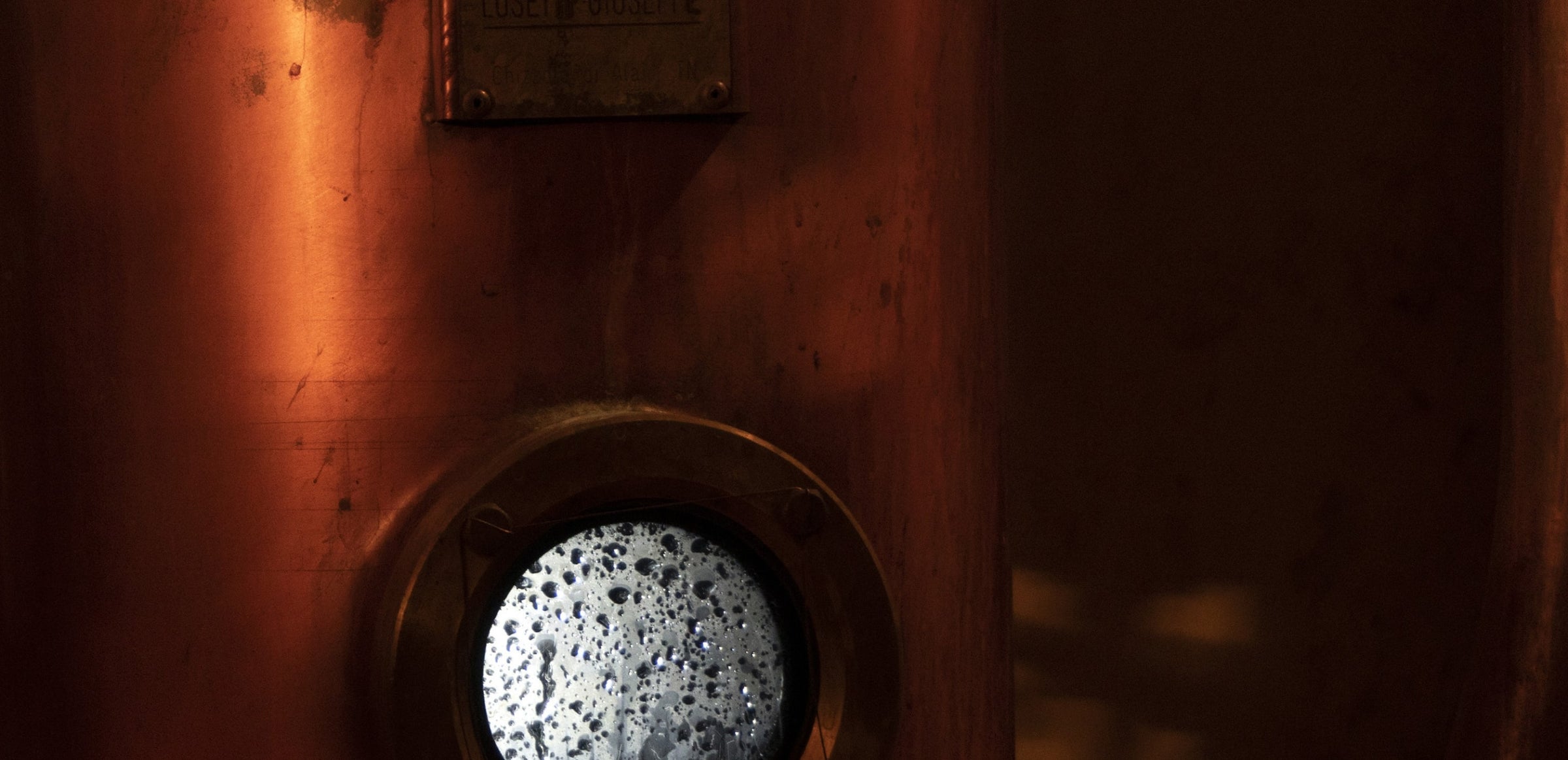 Close up of some machinary used during the whisky creation process with a port hole window covered in steam